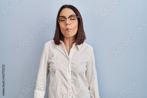 Young hispanic woman standing over white background making fish face with lips, crazy and comical gesture. funny expression.