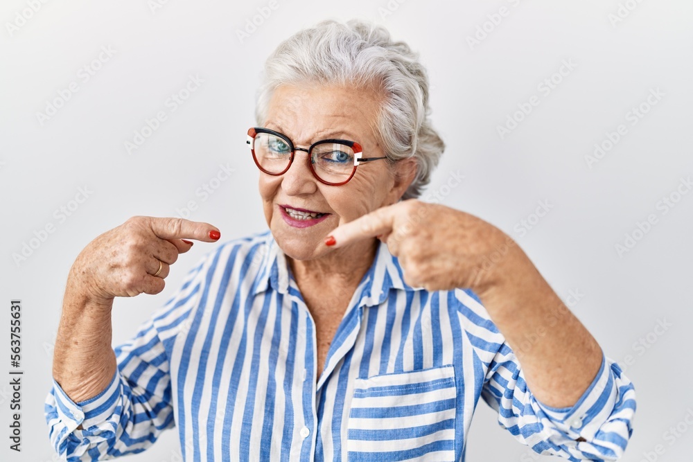 Senior woman with grey hair standing over white background smiling cheerful showing and pointing with fingers teeth and mouth. dental health concept. Senior woman with grey hair standing over white background smiling cheerful showing and pointing with fingers teeth and mouth. dental health concept.