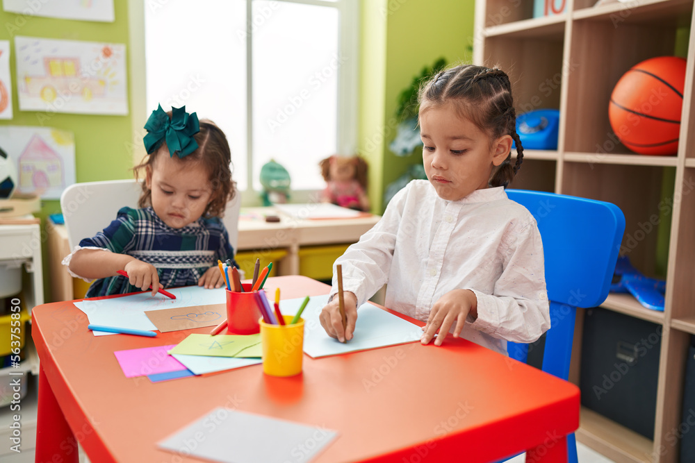 Brother and sister students sitting on table drawing on paper at kindergarten Brother and sister students sitting on table drawing on paper at kindergarten