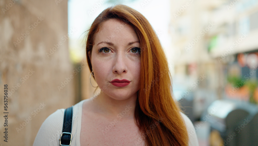 Young redhead woman with relaxed expression standing at street Young redhead woman with relaxed expression standing at street