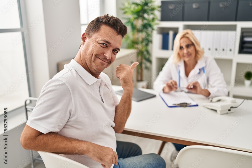 Hispanic man at the doctor smiling happy and positive, thumb up doing excellent and approval sign Hispanic man at the doctor smiling happy and positive, thumb up doing excellent and approval sign
