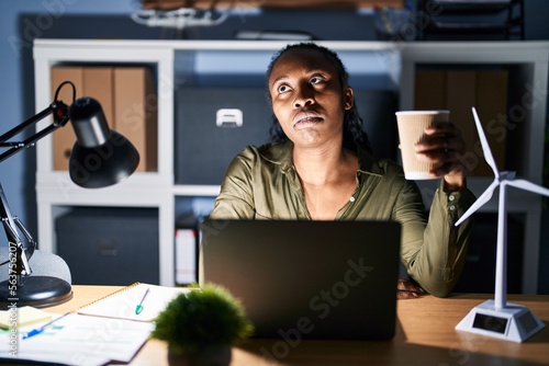 African woman working using computer laptop at night looking sleepy and tired, exhausted for fatigue and hangover, lazy eyes in the morning.