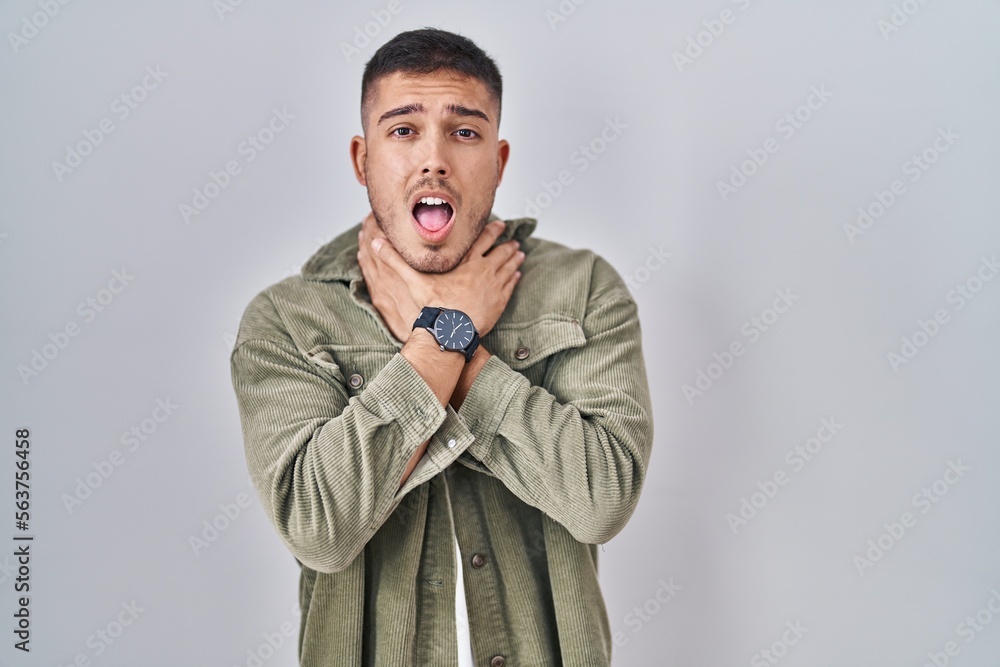 Fototapeta premium Young hispanic man standing over isolated background shouting suffocate because painful strangle. health problem. asphyxiate and suicide concept.