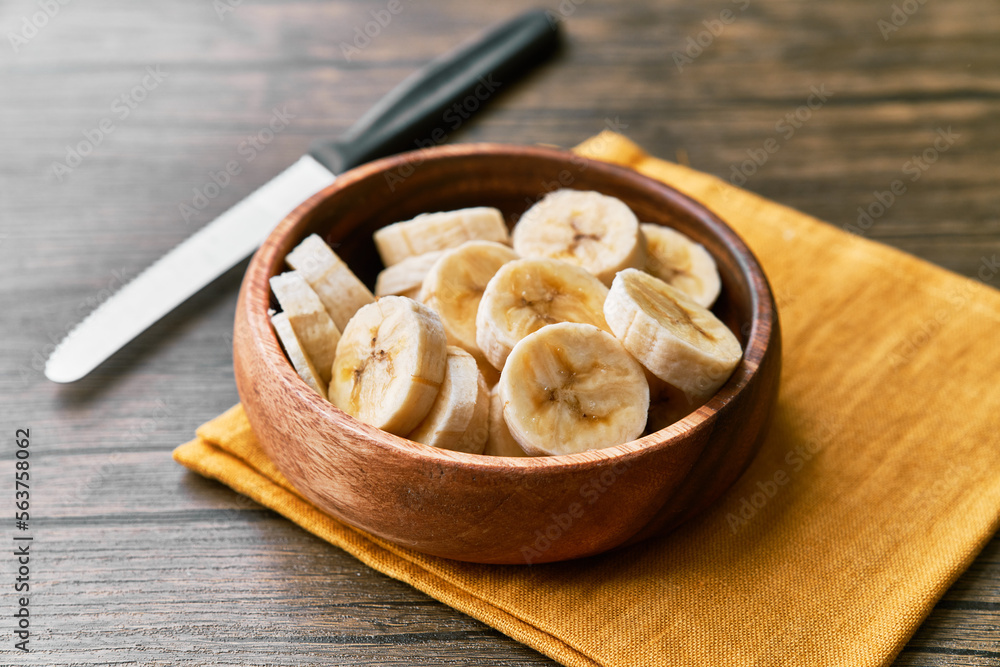 Photo of banana slices in a bowl on a wooden table Photo of banana slices in a bowl on a wooden table