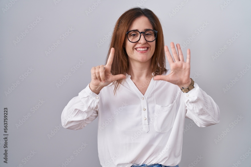 Brunette woman standing over white isolated background showing and pointing up with fingers number seven while smiling confident and happy. Brunette woman standing over white isolated background showing and pointing up with fingers number seven while smiling confident and happy.