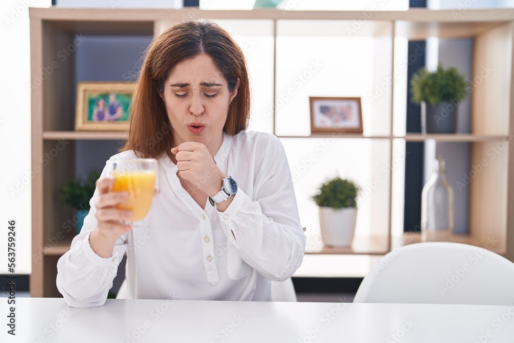 Brunette woman drinking glass of orange juice feeling unwell and coughing as symptom for cold or bronchitis. health care concept. Brunette woman drinking glass of orange juice feeling unwell and coughing as symptom for cold or bronchitis. health care concept.