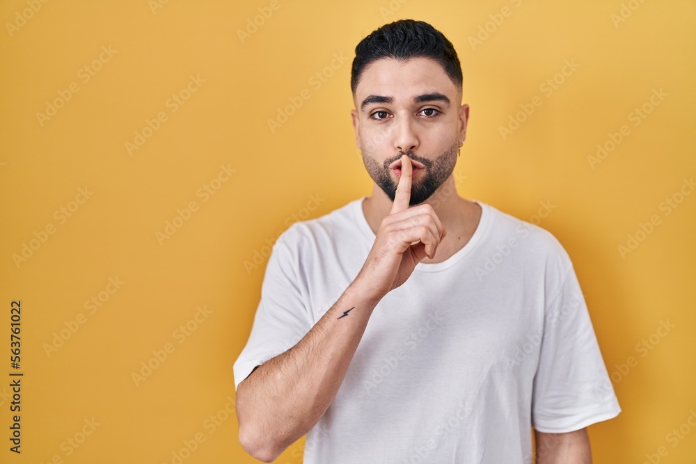 Young handsome man wearing casual t shirt over yellow background asking to be quiet with finger on lips. silence and secret concept. Young handsome man wearing casual t shirt over yellow background asking to be quiet with finger on lips. silence and secret concept.