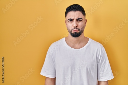 Young handsome man wearing casual t shirt over yellow background depressed and worry for distress, crying angry and afraid. sad expression.