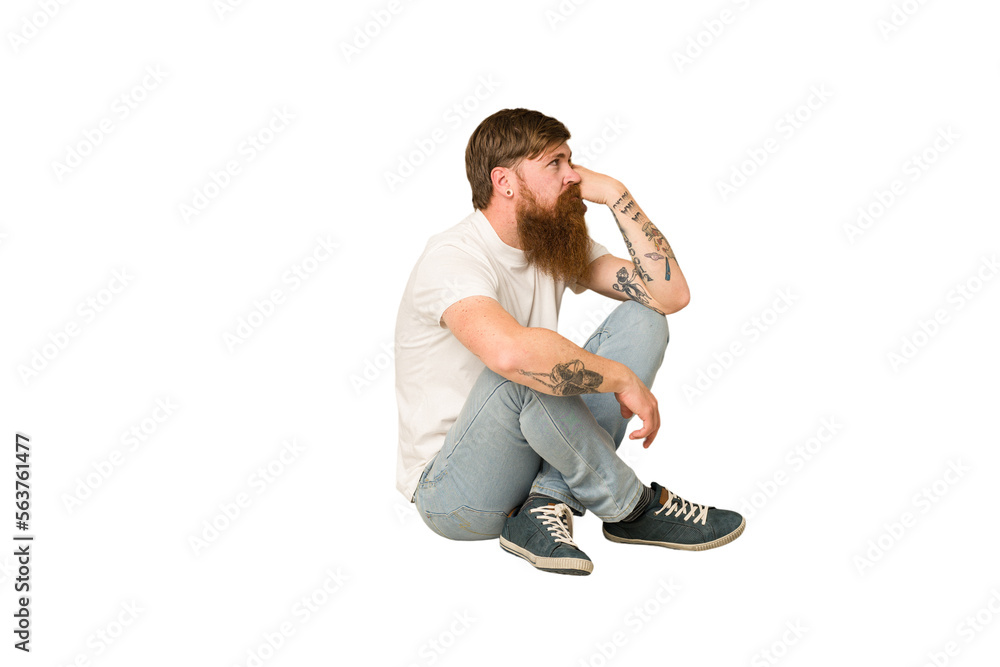 Adult redhead man sitting on the floor isolated Adult redhead man sitting on the floor isolated