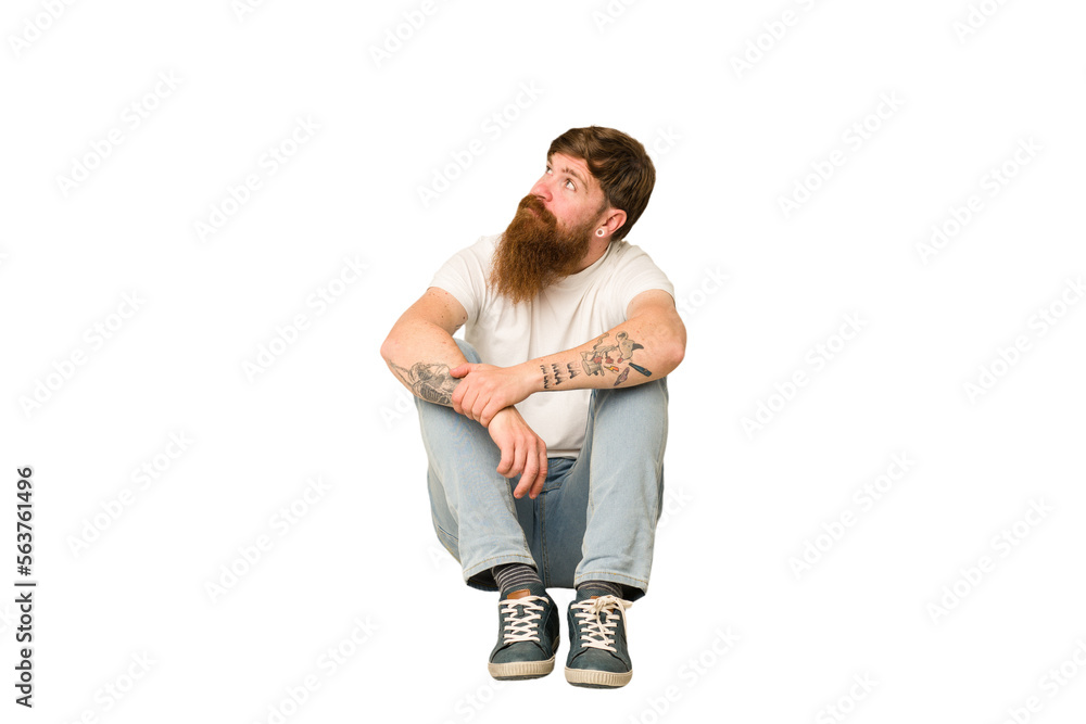 Adult redhead man sitting on the floor isolated Adult redhead man sitting on the floor isolated