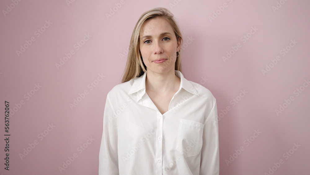 Young blonde woman standing with serious expression over isolated pink background Young blonde woman standing with serious expression over isolated pink background