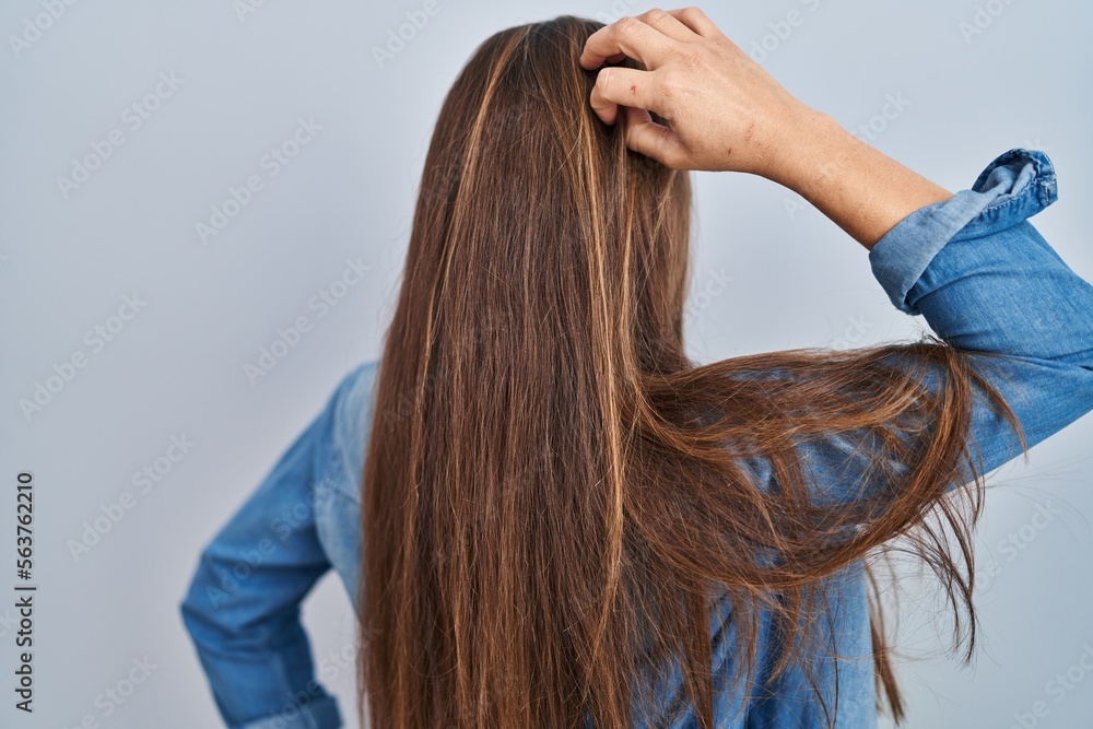 Fototapeta premium Young blonde woman standing over blue background backwards thinking about doubt with hand on head