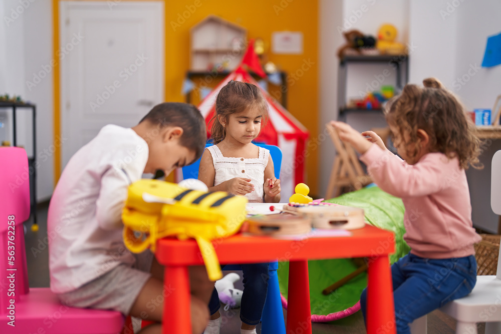 Obraz premium Group of kids preschool students sitting on table drawing on paper at kindergarten