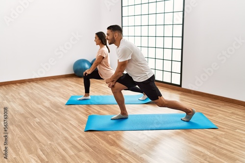 Latin man and woman couple smiling confident stretching at sport center