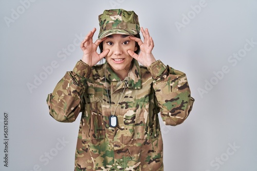 Young south asian woman wearing camouflage army uniform trying to open eyes with fingers, sleepy and tired for morning fatigue