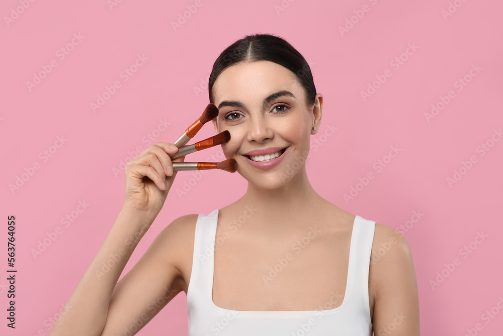 Happy woman with different makeup brushes on pink background Happy woman with different makeup brushes on pink background