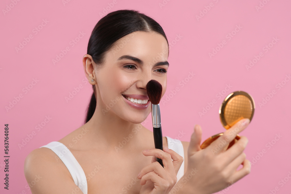Beautiful woman with cosmetic pocket mirror applying makeup on pink background Beautiful woman with cosmetic pocket mirror applying makeup on pink background
