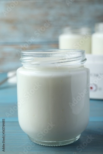 Glass jar with tasty yogurt on blue wooden table