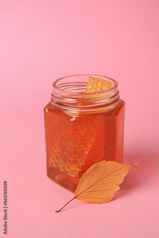 Jar with honey and autumn leaf on pink background Jar with honey and autumn leaf on pink background