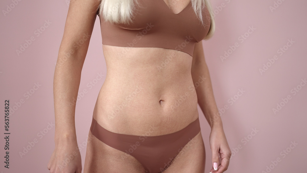 Young blonde woman wearing lingerie over isolated pink background