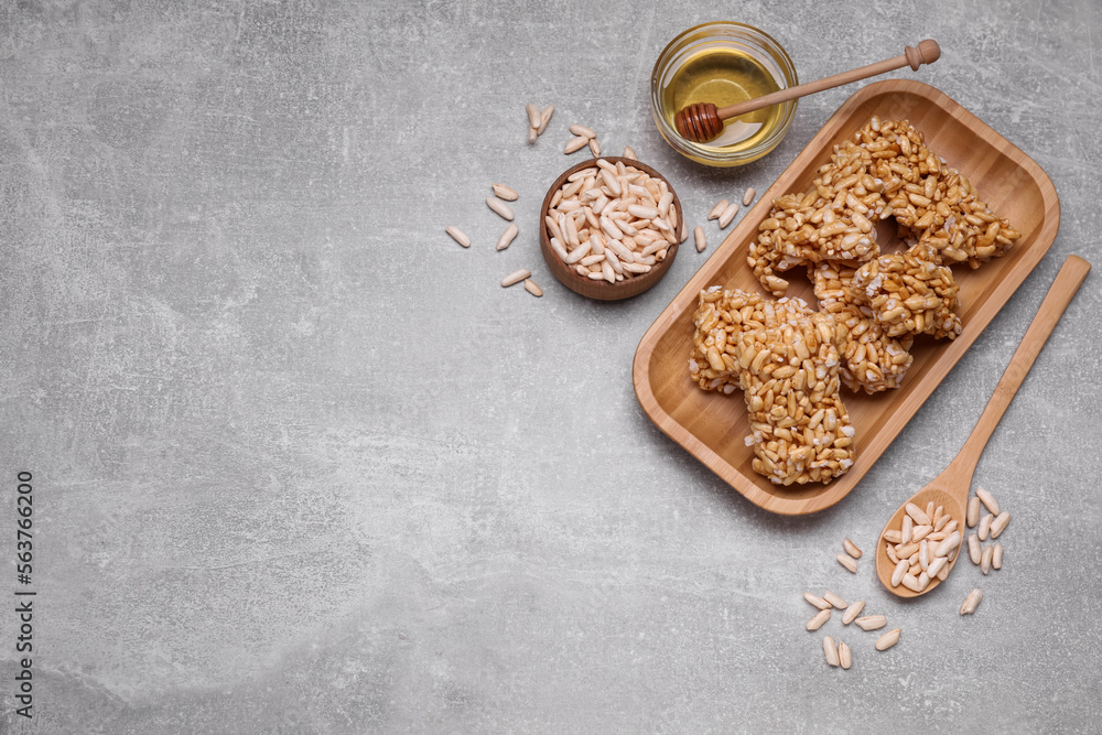 Fototapeta premium Plate with puffed rice pieces (kozinaki) on grey table, flat lay. Space for text
