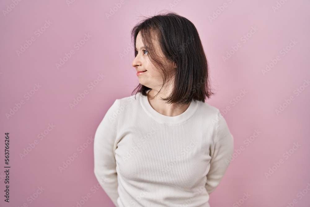 Woman with down syndrome standing over pink background looking away to side with smile on face, natural expression. laughing confident. Woman with down syndrome standing over pink background looking away to side with smile on face, natural expression. laughing confident.