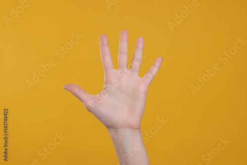 Woman giving high five on orange background, closeup