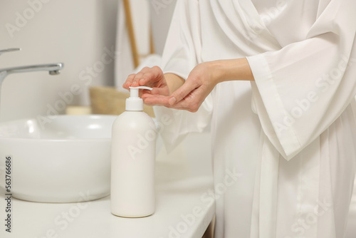 Young woman using body cream in bathroom  closeup