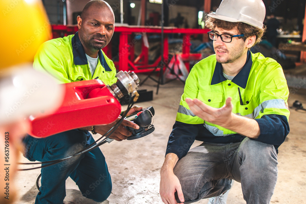 Fototapeta premium Factory worker with safety uniform discussion about robot arm working in factory workplace.