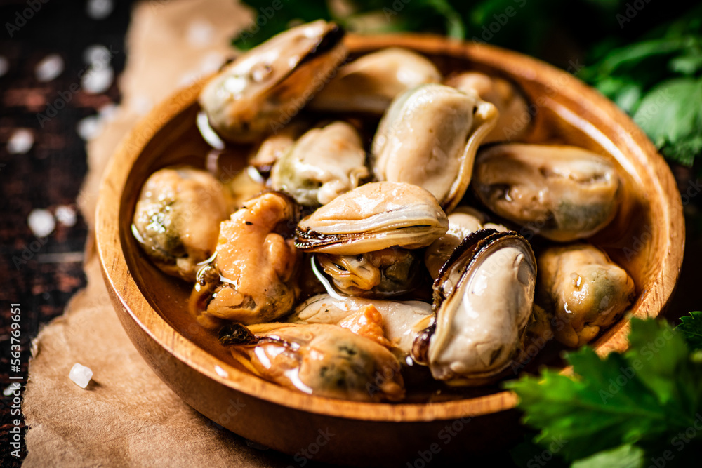 A plate of pickled mussels on paper with parsley. A plate of pickled mussels on paper with parsley.