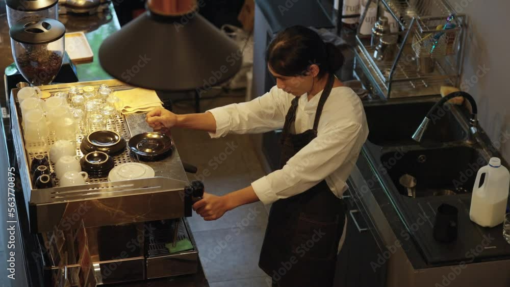 4K Asian man barista making hot espresso shot from coffee maker machine on counter at cafe. Coffee shop owner brewing black coffee serving to customer. Small business restaurant food and drink concept 4K Asian man barista making hot espresso shot from coffee maker machine on counter at cafe. Coffee shop owner brewing black coffee serving to customer. Small business restaurant food and drink concept