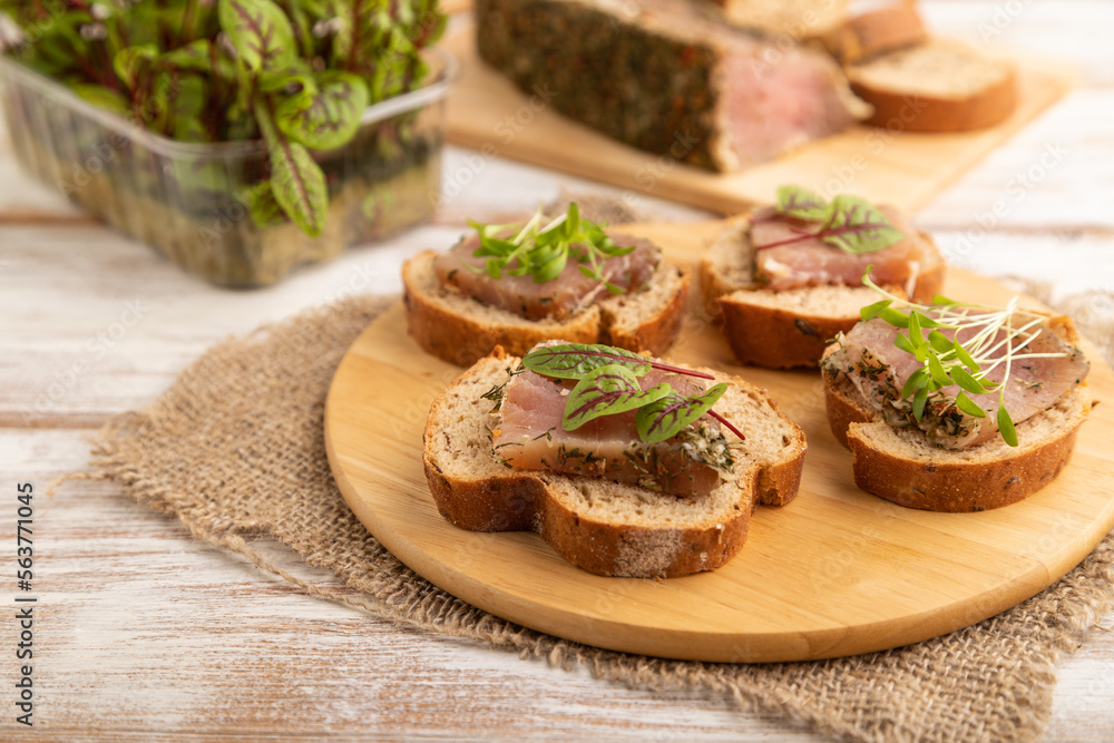 Bread sandwiches with jerky salted meat, sorrel and cilantro microgreen on white. side view, selective focus. Bread sandwiches with jerky salted meat, sorrel and cilantro microgreen on white. side view, selective focus.