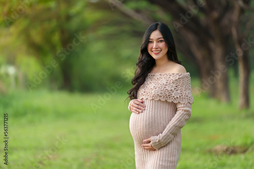 young beautiful pregnant woman stroking her belly in the park.