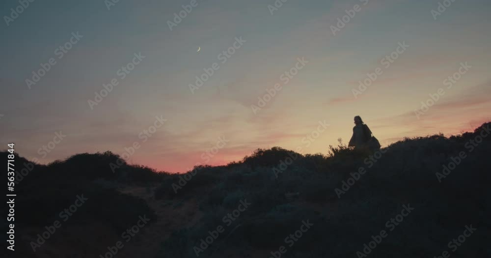 Long haired male photographer taking pictures and enjoying the scenery during sunset and blue hour on the coastline, cliffs of the Algarve, Portugal Long haired male photographer taking pictures and enjoying the scenery during sunset and blue hour on the coastline, cliffs of the Algarve, Portugal