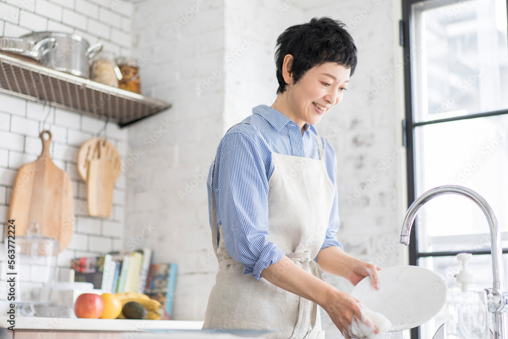 キッチンで環境と肌に優しい食器用洗剤で素手で食器を洗う女性 キッチンで環境と肌に優しい食器用洗剤で素手で食器を洗う女性