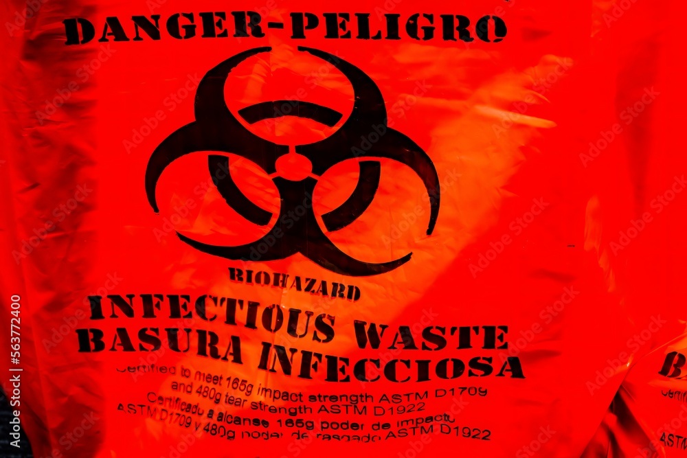 biohazard warning sign or bag in orange for infectious waste in english and spanish Stock Photo