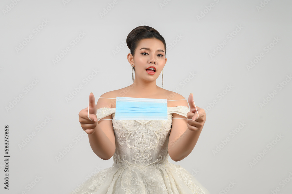 Young asian beautiful bride pose with face mask on white background Young asian beautiful bride pose with face mask on white background