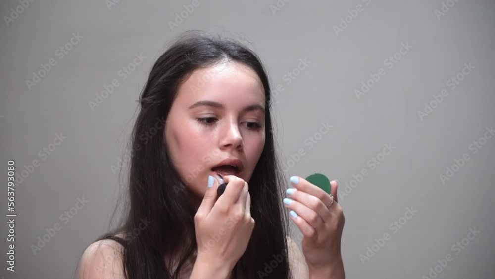 Young girl put lipstick looking in small circle mirror and smile Young girl put lipstick looking in small circle mirror and smile