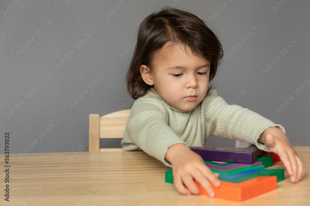 Toddler girl playing with colorful wooden figueres at the table, childhood memories and kids education concept Toddler girl playing with colorful wooden figueres at the table, childhood memories and kids education concept