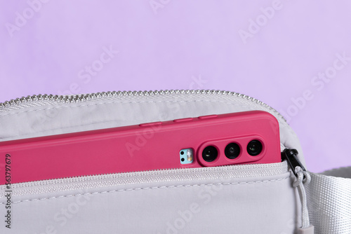A pink phone in a small gray purse