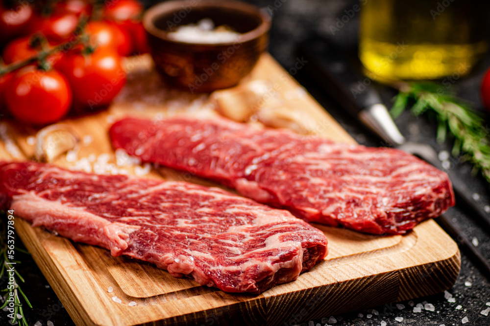 Raw steak on a wooden cutting board. Raw steak on a wooden cutting board.