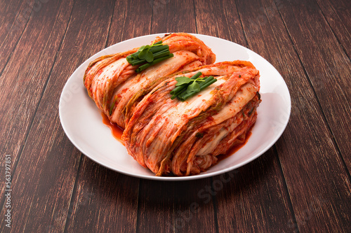 Korean kimchi. Korean traditional cabbage kimchi on white plate. Wood deck background, closeup.