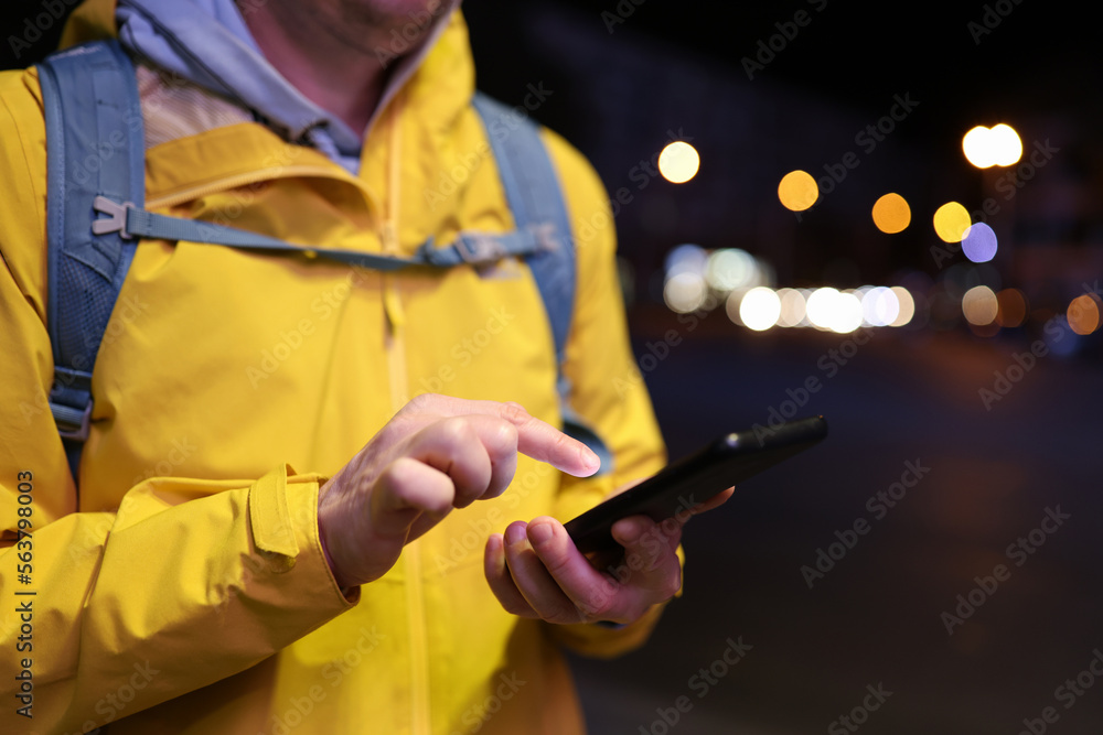 Close-up image of tourist with backpack using his smartphone on the street.
