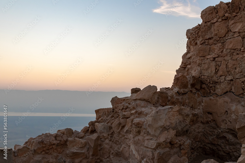 The ruins of fortress wall before sunrise of Massada is fortress built by Herod Great on cliff-top off coast of the Dead Sea. Destroyed by the Romans in the 1st century AD.