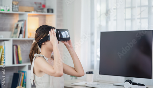 Asian woman smile and play VR game, 3D divice new innovation glasses for entertain at home, asian woman joyful in house on holiday. Happy woman playing metaverse VR technology concept. photo