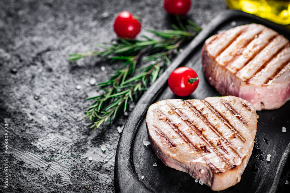 Grilled tuna on a tray with tomatoes and rosemary. Grilled tuna on a tray with tomatoes and rosemary.