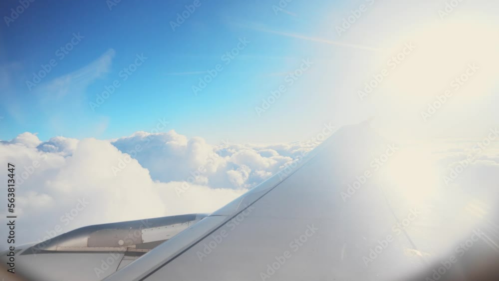 Beautiful view from airplane window to wing and nature breathtaking landscape, mountain peaks in white clouds. Flight to another country. Travel and relaxation, tourism. Sunshine and rays at height. Beautiful view from airplane window to wing and nature breathtaking landscape, mountain peaks in white clouds. Flight to another country. Travel and relaxation, tourism. Sunshine and rays at height.