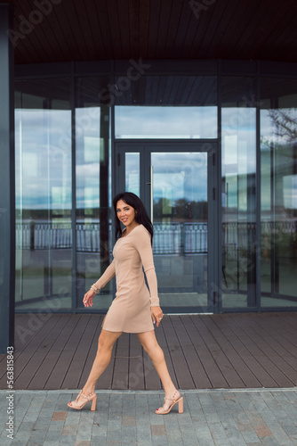 Beautiful young woman brown hair wearing beige color dress walking 