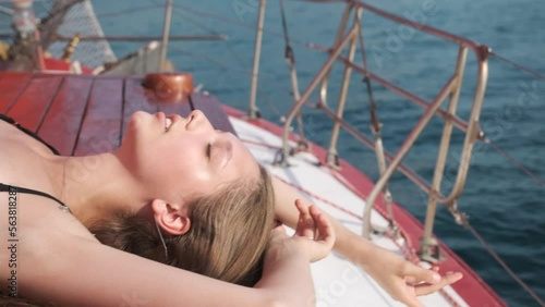 Pretty young girl in swimming suit lying on wooden deck, relaxing and sunbathing