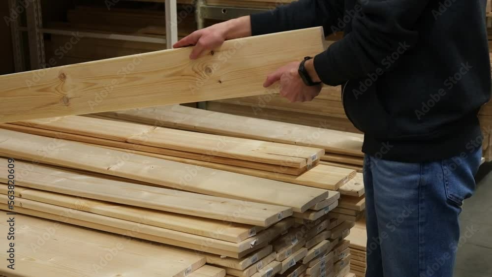A man chooses wooden boards in a hardware store. A man chooses wooden boards in a hardware store.